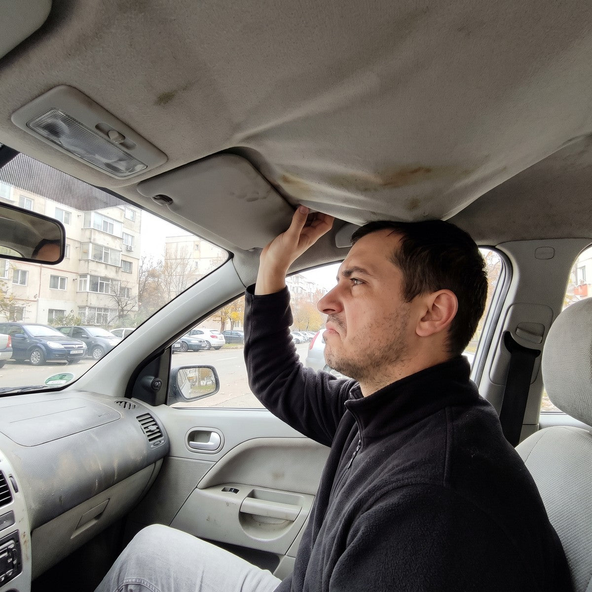 șoferul împinge cu mâna pânza plafonului lăsată peste capul lui