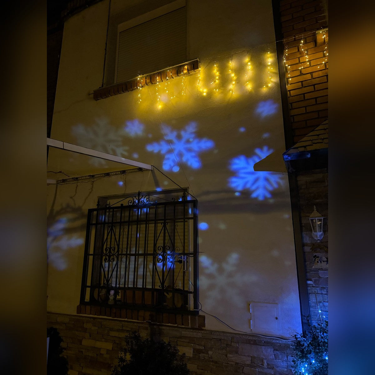 fulgi de nea proiectați pe fațada unei case, seara